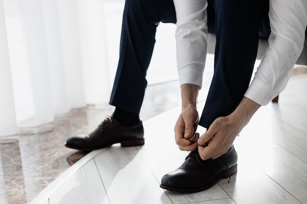 Бесплатное фото Жених завязывает шнурки на ботинки